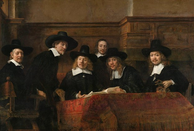 A group of identically dressed men look out from over an open book laid on a table covered by an elaborate red cloth.